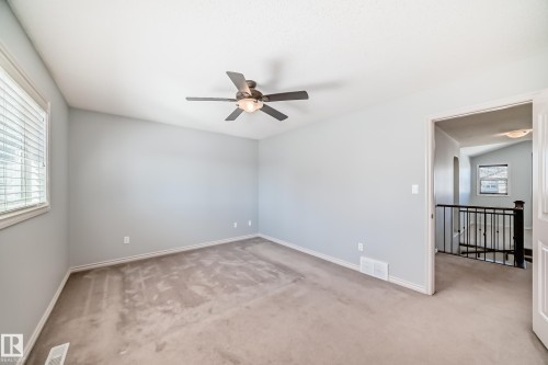 Spacious room featuring vaulted ceilings, a ceiling fan with integrated lighting, window with blinds, light gray wall paint, and neutral carpeting - 6723 19 Avenue, Edmonton, AB 