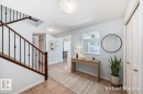 Foyer featuring ceramic tile flooring, a wood and iron staircase, and light blue wall tones - 6723 19 Avenue, Edmonton, AB 