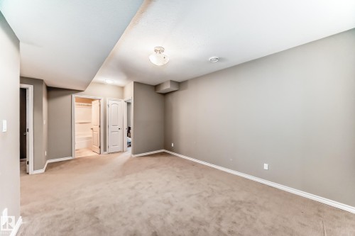 Carpeted room with neutral-toned walls, white trim, and a semi-flush mount ceiling fixture - 6723 19 Avenue, Edmonton, AB 