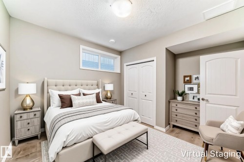 Neutral tone bedroom featuring wood-finish flooring, a double bi-fold closet with arched paneling, and an upper horizontal window - 6723 19 Avenue, Edmonton, AB 