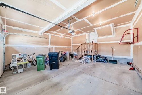 Spacious garage featuring a concrete floor, exposed ceiling joists, and an interior staircase providing access - 6723 19 Avenue, Edmonton, AB 