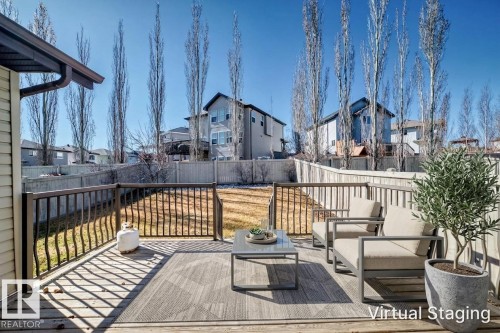 Spacious wood deck featuring a dark railing, leading to a sloped backyard with a privacy fence - 6723 19 Avenue, Edmonton, AB 