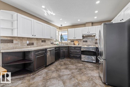 Kitchen featuring two-tone cabinetry, stainless steel appliances, tile flooring, and a tiled backsplash - 86 Westpark Way, Fort Saskatchewan, AB - Indoor Photo Showing Kitchen With Stainless Steel Kitchen
