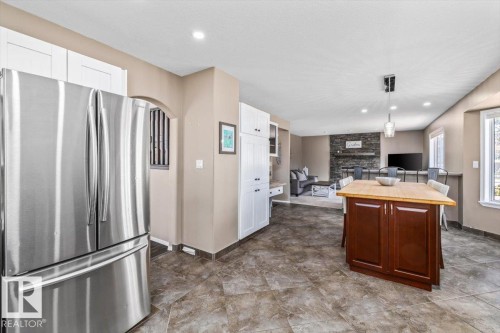 Kitchen featuring stainless steel refrigerator, white cabinetry, and tiled flooring - 86 Westpark Way, Fort Saskatchewan, AB - Indoor Photo Showing Kitchen