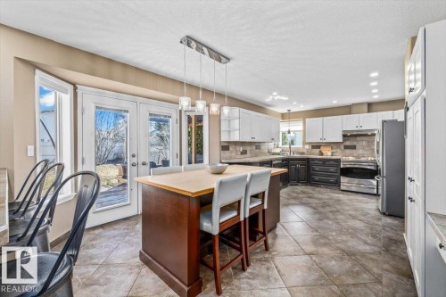 Spacious kitchen featuring a central island with wood countertop, stainless steel appliances, and two-tone cabinetry with ample storage - 86 Westpark Way, Fort Saskatchewan, AB - Indoor