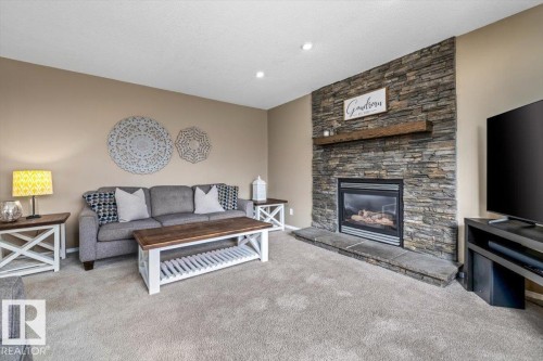 Stacked stone fireplace with a wood mantle and gas insert - 86 Westpark Way, Fort Saskatchewan, AB - Indoor Photo Showing Living Room With Fireplace