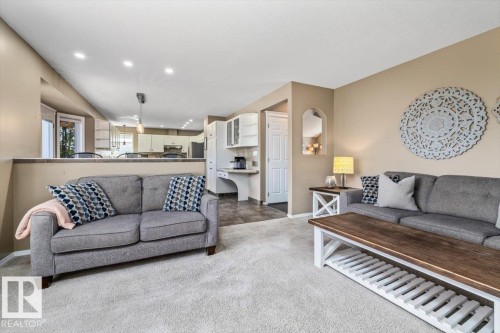 Carpeted living area with recessed lighting, featuring neutral wall tones and a partial wall separating a kitchen area - 86 Westpark Way, Fort Saskatchewan, AB - Indoor Photo Showing Living Room