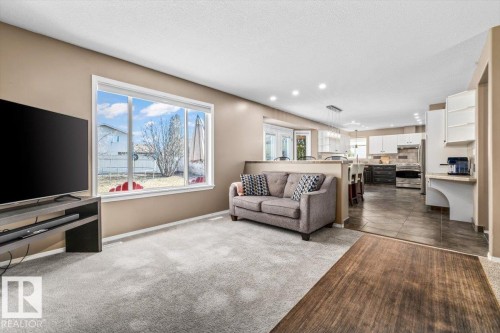 Open-concept living area with light-toned walls, gray carpeting, and a large picture window - 86 Westpark Way, Fort Saskatchewan, AB - Indoor Photo Showing Living Room