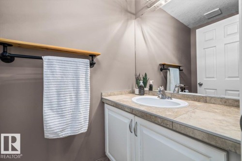Bathroom vanity with a drop-in sink, chrome faucet, and tiled countertop - 86 Westpark Way, Fort Saskatchewan, AB - Indoor Photo Showing Bathroom