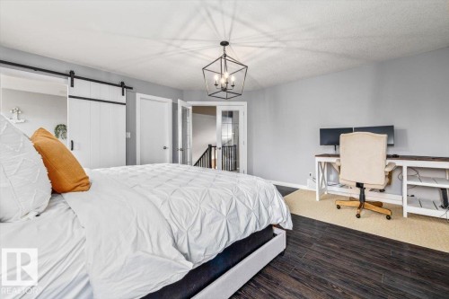 Spacious room featuring dark wood-finish flooring and a vaulted ceiling with a geometric chandelier - 86 Westpark Way, Fort Saskatchewan, AB - Indoor Photo Showing Bedroom