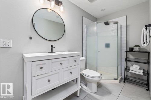 Bathroom featuring a white vanity with integrated sink, black matte faucet, round framed mirror, and a glass-enclosed shower with subway tile surround - 86 Westpark Way, Fort Saskatchewan, AB - Indoor Photo Showing Bathroom