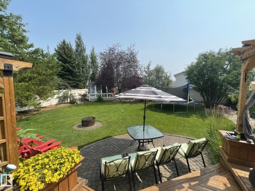Expansive backyard featuring a paver patio, integrated fire pit, and a wooden deck with a pergola structure - 86 Westpark Way, Fort Saskatchewan, AB - Outdoor With Deck Patio Veranda