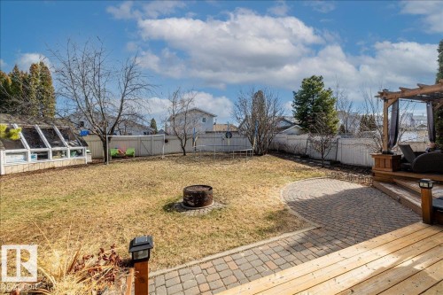 Expansive backyard featuring a wood deck, a patio with paver stones, a pergola structure, a greenhouse, and a fire pit - 86 Westpark Way, Fort Saskatchewan, AB - Outdoor With Deck Patio Veranda