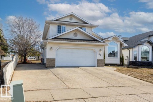 Two-story residence featuring light-colored siding, an attached two-car garage, and a concrete driveway - 86 Westpark Way, Fort Saskatchewan, AB - Outdoor With Facade