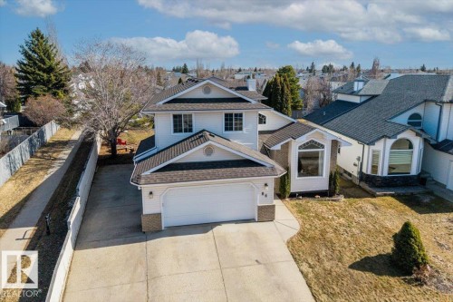 Two-story residence featuring a white siding exterior with stone accents, an attached garage, and a concrete driveway - 86 Westpark Way, Fort Saskatchewan, AB - Outdoor With Facade