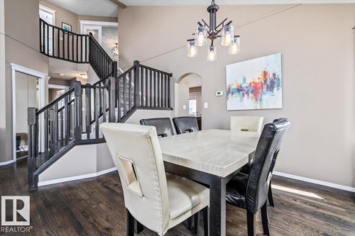 Dining area featuring wood-finish flooring, a contemporary chandelier, and an arched entry - 86 Westpark Way, Fort Saskatchewan, AB - Indoor Photo Showing Dining Room