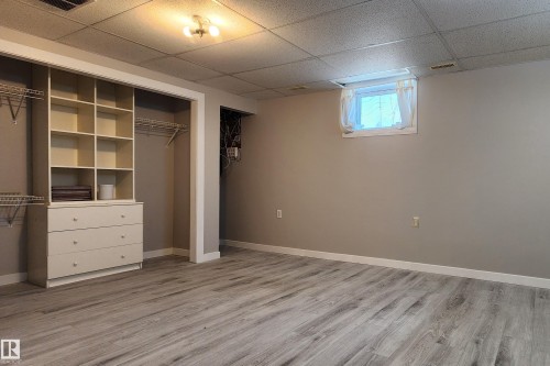 Spacious room featuring wood-finish flooring and neutral wall tones - 4911 106 Street, Edmonton, AB - Indoor