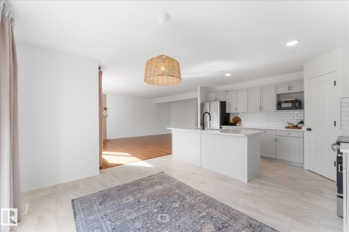 Kitchen featuring white cabinetry, white subway tile backsplash, and a central island with a black faucet - 326 Silver Berry Road, Edmonton, AB - Indoor Photo Showing Kitchen