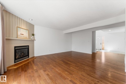 Open-concept living space featuring wood-finish flooring and a built-in fireplace with a mantel - 326 Silver Berry Road, Edmonton, AB - Indoor Photo Showing Other Room With Fireplace