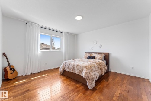 Bright room featuring rich wood-finish flooring, white walls, and a large window with white curtain panels - 326 Silver Berry Road, Edmonton, AB - Indoor Photo Showing Bedroom
