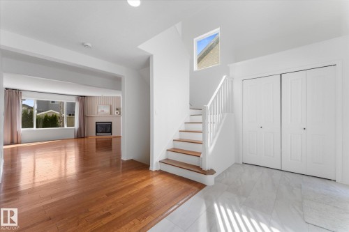 Entryway featuring polished wood-finish flooring transitioning to large format tile, a staircase with wood treads and white risers, and bi-fold closet doors - 326 Silver Berry Road, Edmonton, AB - Indoor Photo Showing Other Room