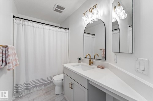 Contemporary bathroom featuring a light gray vanity with gold-finish hardware, a white countertop, and a built-in sink - 326 Silver Berry Road, Edmonton, AB - Indoor Photo Showing Bathroom