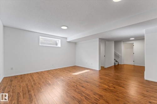 Spacious room featuring wood-finish flooring, white painted walls, and recessed lighting - 326 Silver Berry Road, Edmonton, AB - Indoor