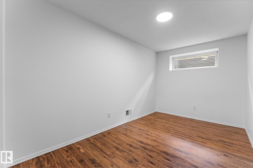 Bright room featuring wood-finish flooring, white baseboards, a single flush-mount ceiling light, and a horizontal window with blinds - 326 Silver Berry Road, Edmonton, AB - Indoor Photo Showing Other Room