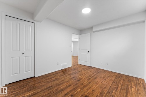 Interior room featuring warm wood-finish flooring, white walls, and a white bi-fold closet door - 326 Silver Berry Road, Edmonton, AB - Indoor Photo Showing Other Room