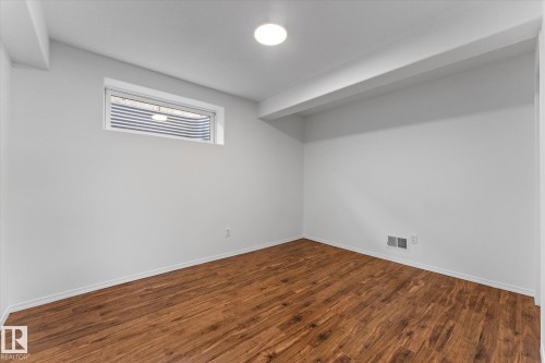 Room featuring wood-finish flooring, white painted walls, a window well, and a flush-mount ceiling light - 326 Silver Berry Road, Edmonton, AB - Indoor Photo Showing Other Room