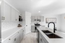 Modern kitchen featuring light gray cabinetry, white countertops, subway tile backsplash, stainless steel appliances, and a central island with a double basin sink and matte black faucet - 326 Silver Berry Road, Edmonton, AB  - Indoor Photo Showing Kitchen With Double Sink With Upgraded Kitchen 