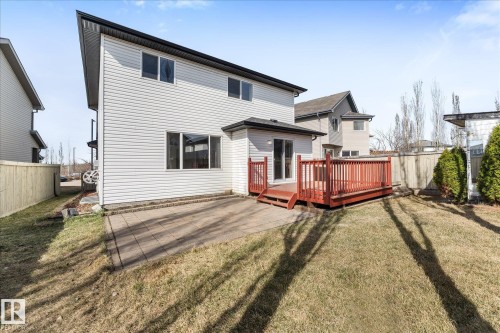 Rear exterior featuring a red-stained wooden deck, ground-level patio, and light-colored siding - 326 Silver Berry Road, Edmonton, AB - Outdoor With Deck Patio Veranda With Exterior
