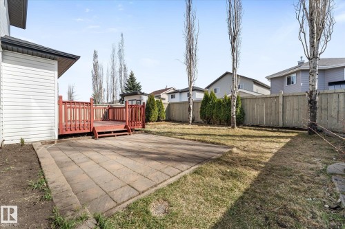 Expansive backyard featuring a wood deck with red railing, a paver patio, mature trees, and a privacy fence - 326 Silver Berry Road, Edmonton, AB - Outdoor