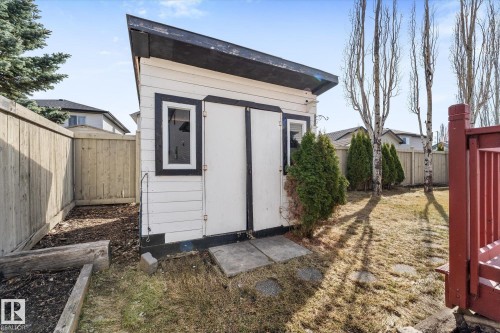 Freestanding storage shed with white siding and black trim, featuring dual entry doors and a single window - 326 Silver Berry Road, Edmonton, AB - Outdoor