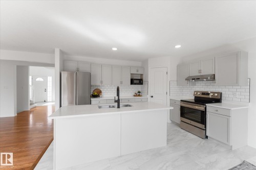 Contemporary kitchen featuring a white center island, light gray cabinetry, stainless steel appliances, a white subway tile backsplash, and recessed lighting - 326 Silver Berry Road, Edmonton, AB - Indoor Photo Showing Kitchen With Stainless Steel Kitchen