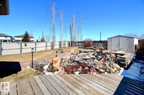Expansive fenced backyard featuring a wood deck, a rock garden, a storage shed, and a fire pit area - 2927 30 Street, Edmonton, AB - Outdoor