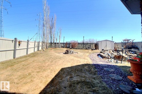 Spacious backyard featuring a dedicated fire pit area, a stone and gravel pathway, and a detached storage shed - 2927 30 Street, Edmonton, AB - Outdoor