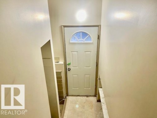 Entryway with a white door featuring a decorative arched window and transom, light-colored walls, and tiled flooring - 8507 35 Avenue, Edmonton, AB - Indoor Photo Showing Other Room