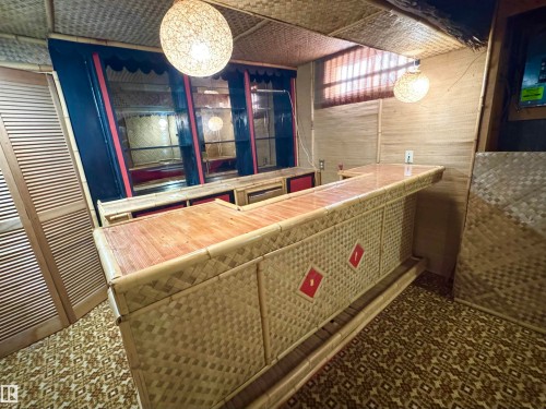 The property features a dedicated bar area with a built-in counter, patterned woven wall coverings, and decorative overhead lighting - 8507 35 Avenue, Edmonton, AB - Indoor Photo Showing Other Room