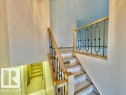The property features a staircase with light-toned wooden handrails and black decorative balusters, leading to an open landing area - 8507 35 Avenue, Edmonton, AB  - Indoor Photo Showing Other Room 