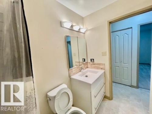 Bathroom featuring a white vanity with an integrated sink, a rectangular mirror, and a tile backsplash - 8507 35 Avenue, Edmonton, AB - Indoor Photo Showing Bathroom
