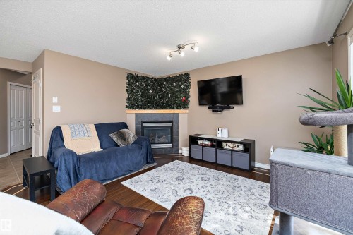 Living area featuring wood-finish flooring, a fireplace with a stone surround and mantel, and track lighting - 992 Regency Drive, Sherwood Park, AB - Indoor Photo Showing Living Room With Fireplace