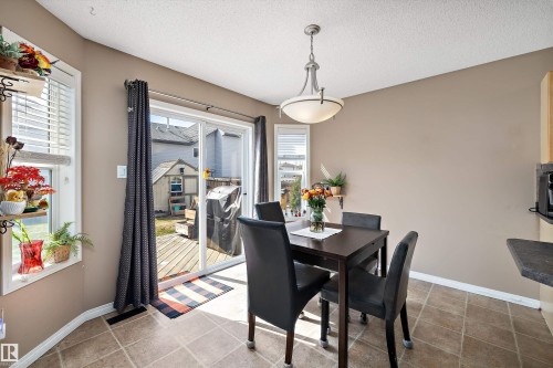 Dining area featuring ceramic tile flooring, a glass-paned sliding door, and a built-in window with white blinds - 992 Regency Drive, Sherwood Park, AB - Indoor Photo Showing Dining Room
