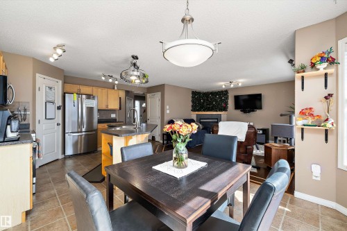 Dining area with a dark wood-finish table and leather-look chairs, featuring a contemporary pendant light fixture - 992 Regency Drive, Sherwood Park, AB - Indoor Photo Showing Dining Room