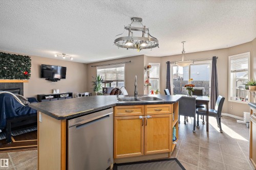 Kitchen island featuring a double-basin sink, stainless steel dishwasher, and light wood-finish cabinetry - 992 Regency Drive, Sherwood Park, AB - Indoor
