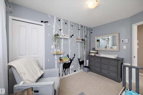 Bedroom featuring light gray walls with a decorative forest mural, carpet flooring, a white bi-fold closet door, and a flush-mount ceiling light fixture - 992 Regency Drive, Sherwood Park, AB - Indoor