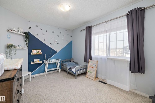 Carpeted room featuring a window with white sills, multiple wall shelves, and a ceiling-mounted light fixture - 992 Regency Drive, Sherwood Park, AB - Indoor Photo Showing Bedroom