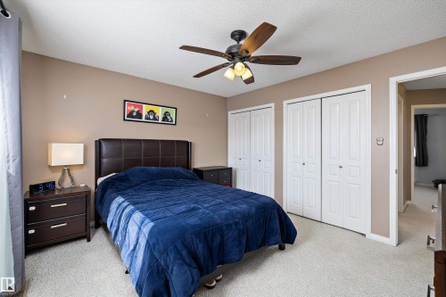 Carpeted bedroom featuring a textured ceiling, a ceiling fan with integrated lighting, and two sets of bi-fold closet doors - 992 Regency Drive, Sherwood Park, AB - Indoor Photo Showing Bedroom