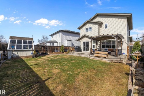 Expansive backyard featuring a manicured lawn, a multi-level deck with a wooden pergola, a greenhouse structure, and a wood privacy fence - 992 Regency Drive, Sherwood Park, AB - Outdoor With Deck Patio Veranda