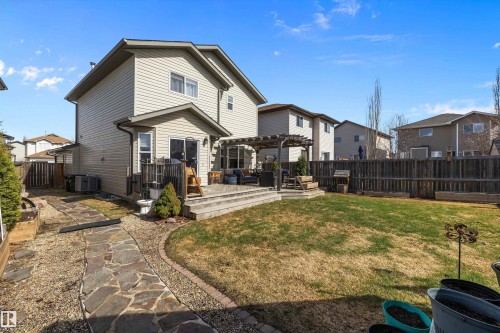 Rear exterior showcasing a multi-level wood deck with pergola, extensive lawn area, stone pathway, and wood privacy fencing - 992 Regency Drive, Sherwood Park, AB - Outdoor